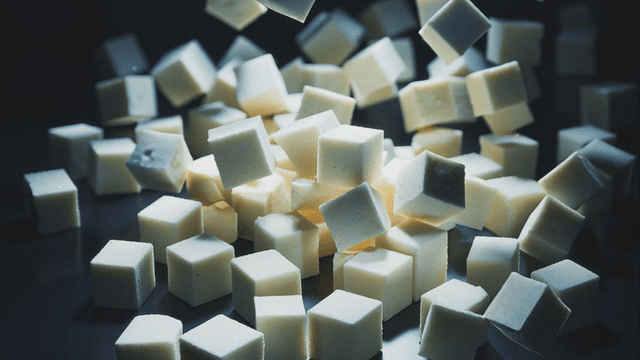 Falling white sugar cubes stacking on surface