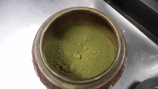 A jar of green tea powder being opened