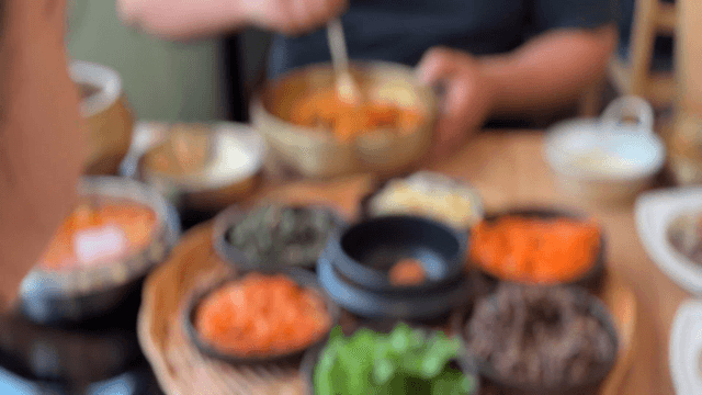 People mixing bibimbap with various vegetables