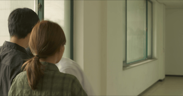 Man leaving after talking with two people in hallway