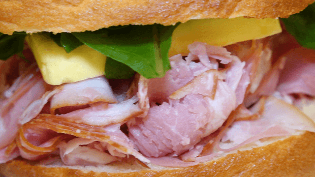 A sandwich with ham and greens on a plate