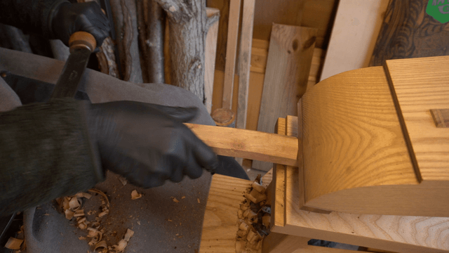 Wood branch being carved with a drawknife