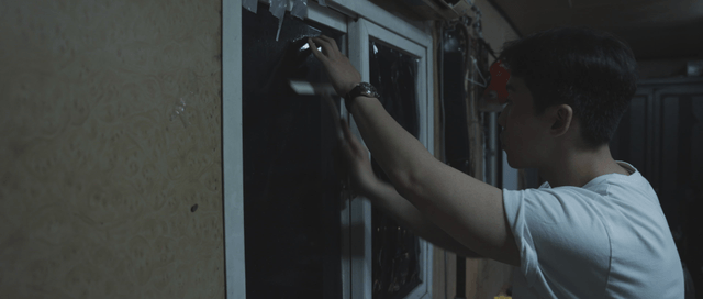Man attaching a blackout sheet to a window