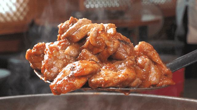 Spicy stir-fried chicken dish scooped with a spatula