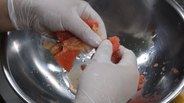 Hands peeling grapefruit in a metal bowl