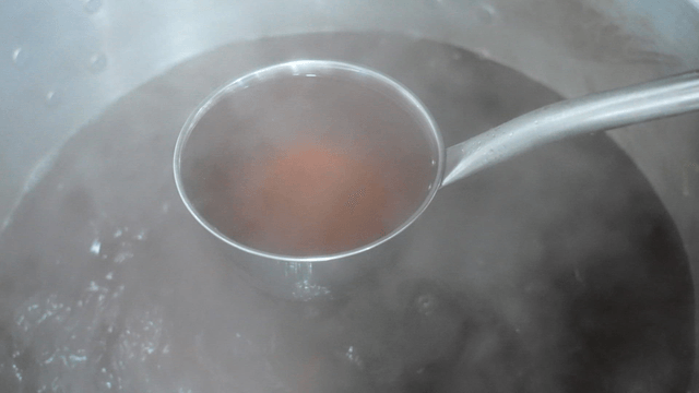 Ladle scooping hot rich brown broth