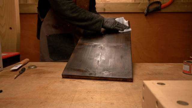 Woodworker applying finish to a wooden board