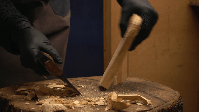 Artisan carving wood with an axe in workshop