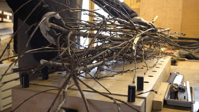 Woodcraft artisan placing wooden branches on workbench