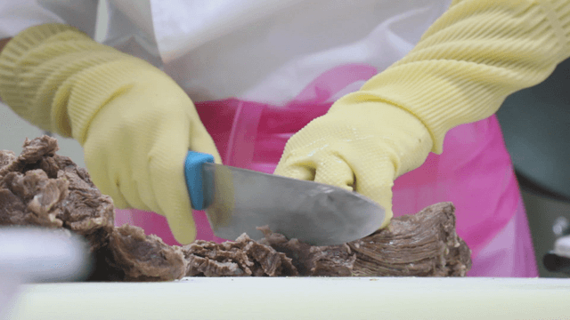 Person slicing cooked beef with a knife