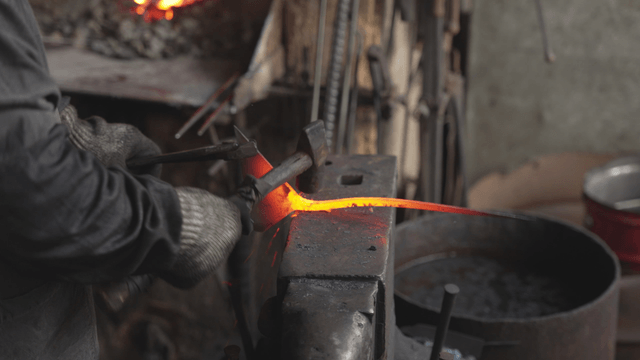 Blacksmith forging hot metal in workshop