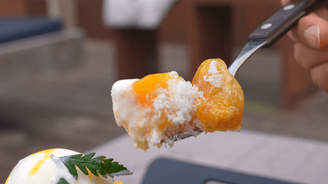Spoon scooping mango bingsu topped with ice cream