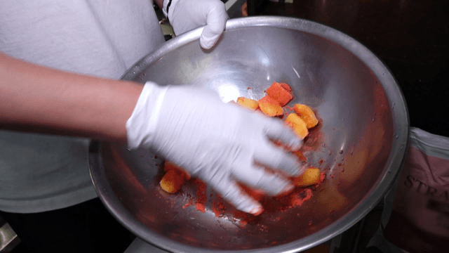 Mixing strawberry powder with mango pieces in kitchen