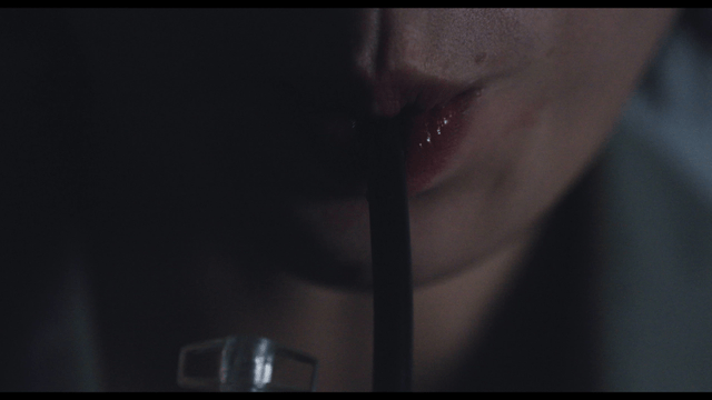 Close-up of woman drinking blood from pack with straw