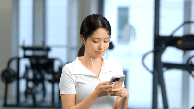 Woman using smartphone with earphones at gym