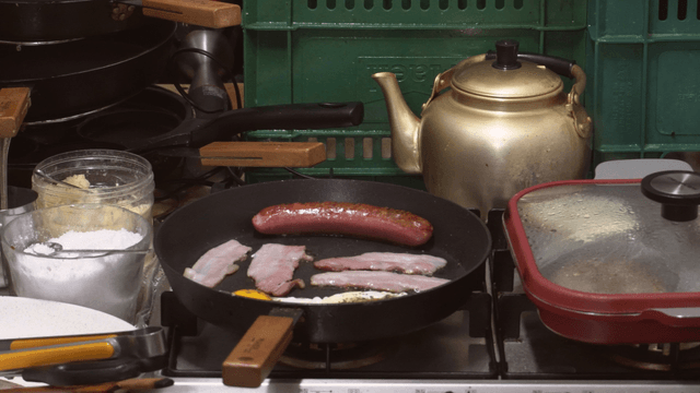 Sausage and bacon grilling in a frying pan