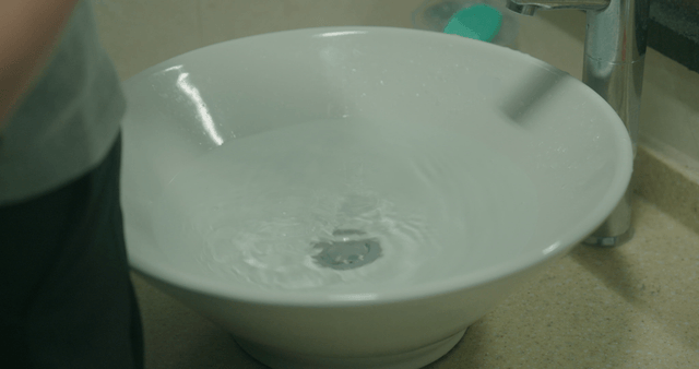Hands being washed in a white basin