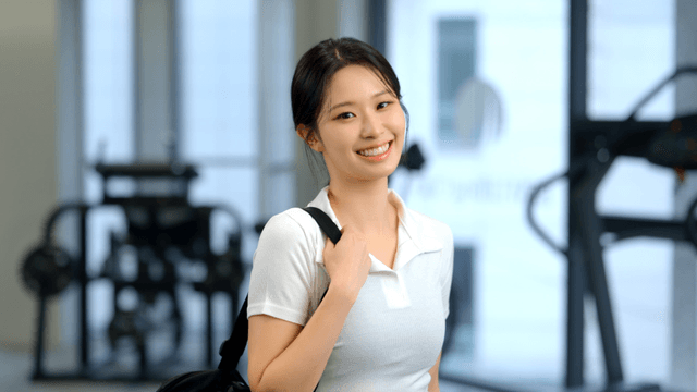 Smiling woman facing forward with a bag in a gym