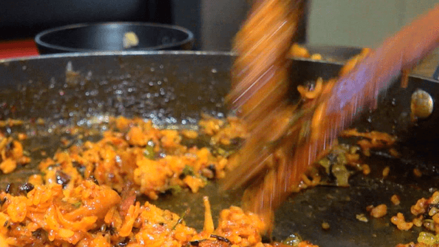 Wooden spatula carefully stir-frying iron plate fried rice